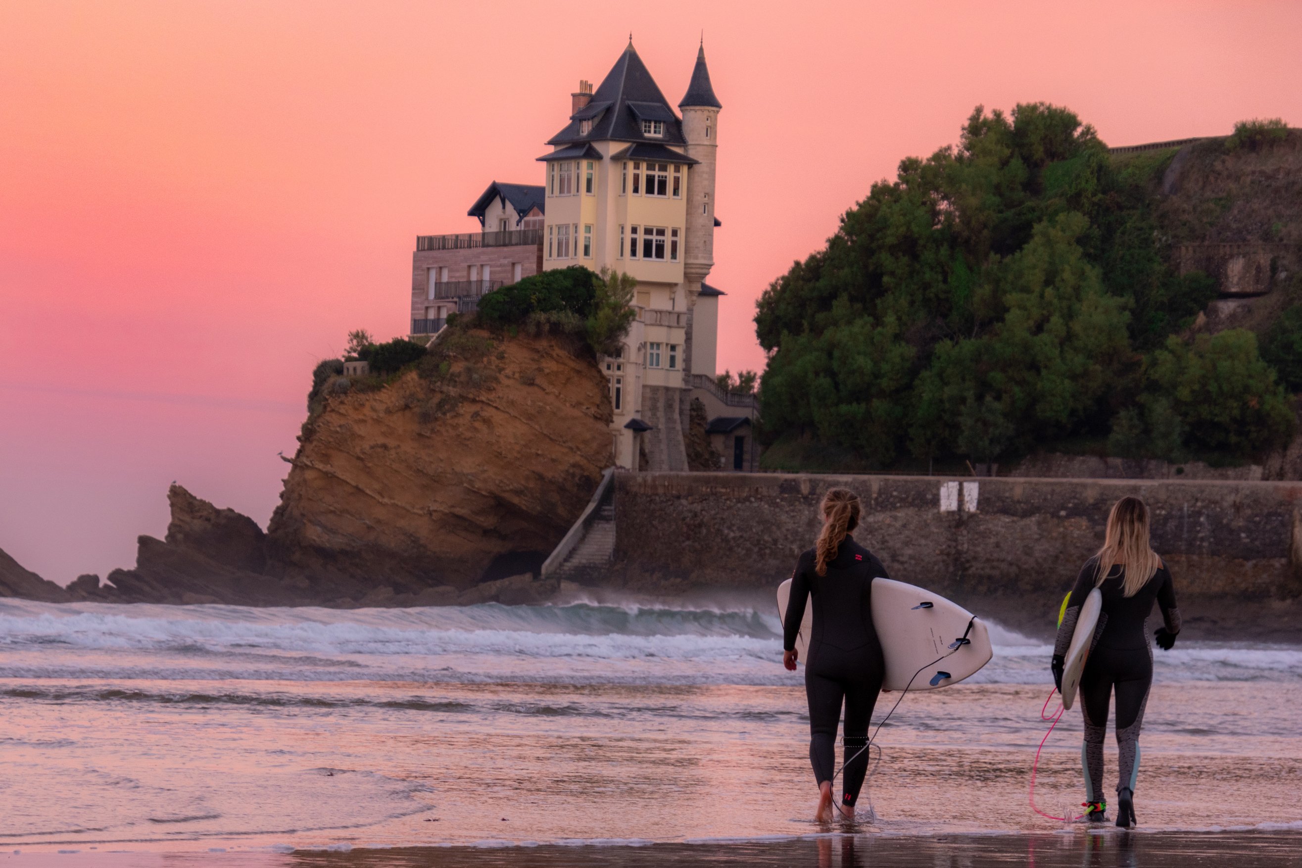 Surfeurs le long de la plage durant un coucher de soleil